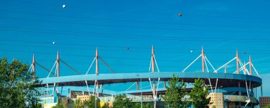 Exterior shot of the Estadio Municipal de Aveiro in Portugal, a stadium known for its colorful and modern architectural design by Tomas Taveira, seen from a distance on a sunny day.	