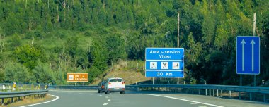 Portekiz 'deki yoğun yeşil okaliptüs ormanından geçen çok şeritli bir otoyolun hareket halindeki bir görüntüsü..