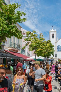 Aviero, Portekiz: 15 Ağustos 2023: Aveiro 'da turist ve kafe teraslarının önünde parlak yaz gökyüzünün altında beyaz bir kilisenin önü.