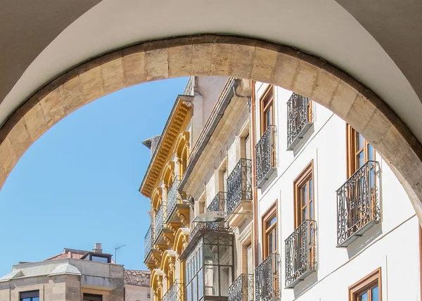 Salamanca, İspanya: 16 Ağustos 2023: Salamanca İspanya 'da güneşli bir meydana açılan zarif taş kemerlerin altında bir caddeyi gösteren orta boy çekim. 