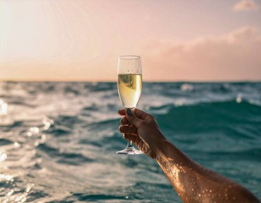 Orta açı, bir kadının kolunun denizin ortasından yukarı doğru yükseldiğini ve elinde şampanya bardağı tuttuğunu gösteriyor. 