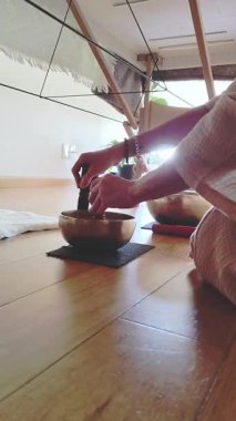 Ahşap zeminde oturmuş kâse oynayan kadın terapistin yakın plan görüntüsü.