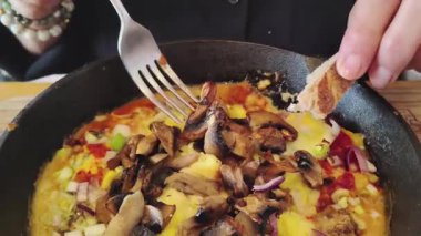 Yüksek açılı yakın çekim videosunda bir kaşık polenta sosu ve mantarla kendini servis eden bir kadın görülüyor.