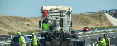 Salamanca, İspanya: 17 Ağustos 2023: Gündüz vakti kırsal bir otoyolda asfalt döşeyen yol işçileri ve ağır makineler, altyapı geliştirme ve takım çalışmalarını gösteriyor.
