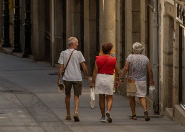Arka planda, Bejar, Castille ve Leon, İspanya 'da dar bir kaldırımda yürüyen üç son sınıf öğrencisinin tam görüntüsü var.