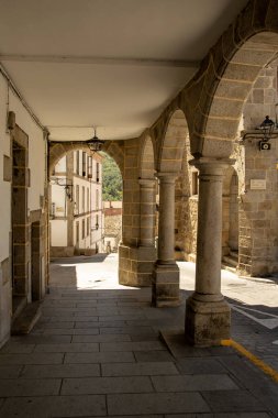 İspanya, Bejar 'da güneşli bir sokağa doğru gölgeli bir taş atari salonundan bakan dikey bir çekim.