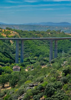 Uzun beton bir viyadük ya da köprünün manzarası yoğun yeşil ormanlarla dolu bir vadiden geçiyor, Castille ve Leon, İspanya