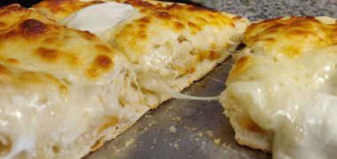 Bir tepside dilimlenmiş peynirli pizza.