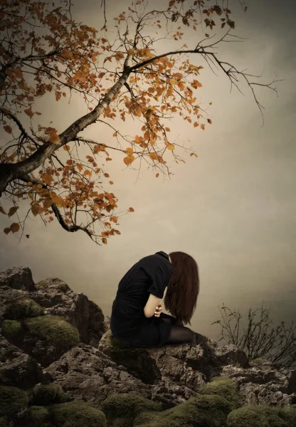 Jong meisje, zittend op een rots — Stockfoto
