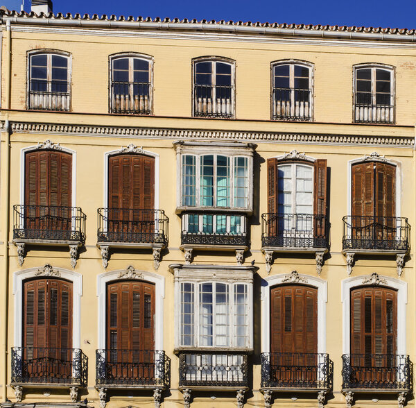 Traditional Andalusian shuttered casement windows in an elegant residential apartment block in the center of Malaga.
