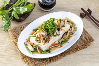 Ahşap masada seramik bir tabakta soya soslu buğulanmış tofu..