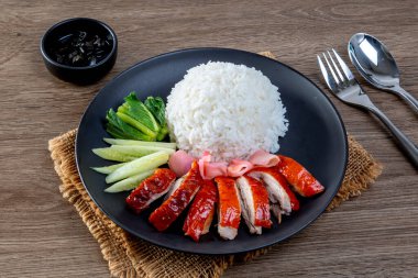 Masadaki siyah tabakta pilav üzerinde ızgara ördek.