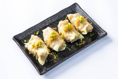 Asya usulü buğulanmış hamur köftesi, siyah seramik tabakta servis edilmiş, beyaz bir arka planda..