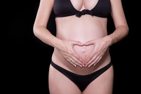 Närbild på en söt gravid mage med svart bakgrund — Stockfoto