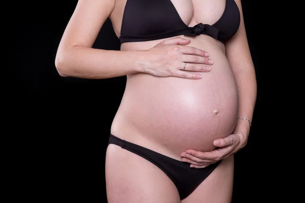 Nahaufnahme eines niedlichen Schwangerschaftsbauchs mit schwarzem Hintergrund lizenzfreie Stockbilder