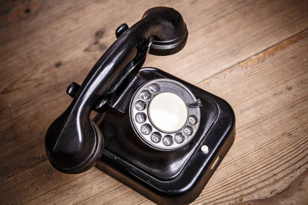 Old black phone with dust and scratches on wooden floor — Stock Photo, Image