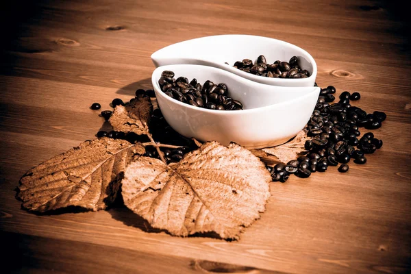 Tazze con chicchi di caffè su un tavolo di legno — Foto Stock