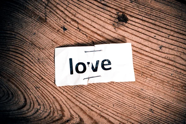 "Love" word written on torn and stapled paper — Stock Photo, Image