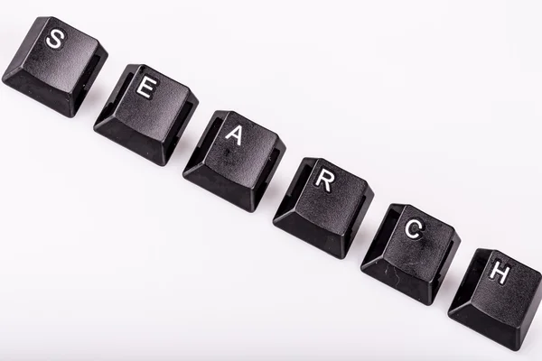 Текстовый поиск, формируемый клавишами клавиатуры на белом заднем плане — стоковое фото