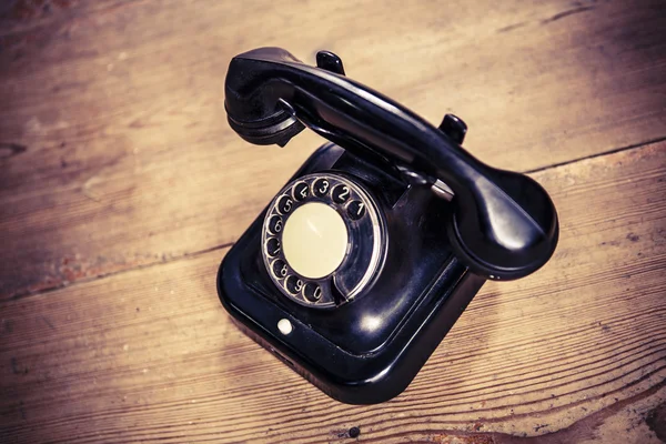 Vecchio telefono nero con polvere e graffi sul pavimento in legno — Foto Stock