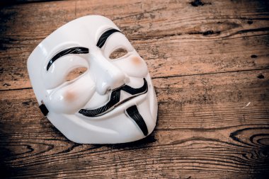 White anonymous mask on wood background