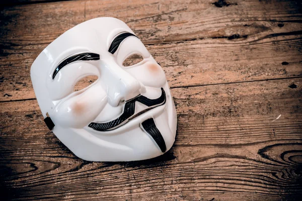 White anonymous mask on wood background — Stock Photo, Image