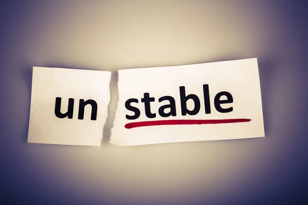 Слово "нестабильный" изменилось на "стабильный" на порванной бумаге — стоковое фото