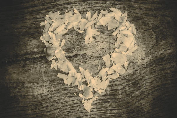 A heart from petals lying on a wooden table — Stock Photo, Image