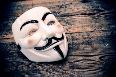 White anonymous mask on wood background