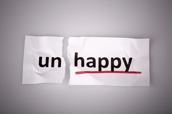 The word unhappy changed to happy on torn paper — Stock Photo, Image