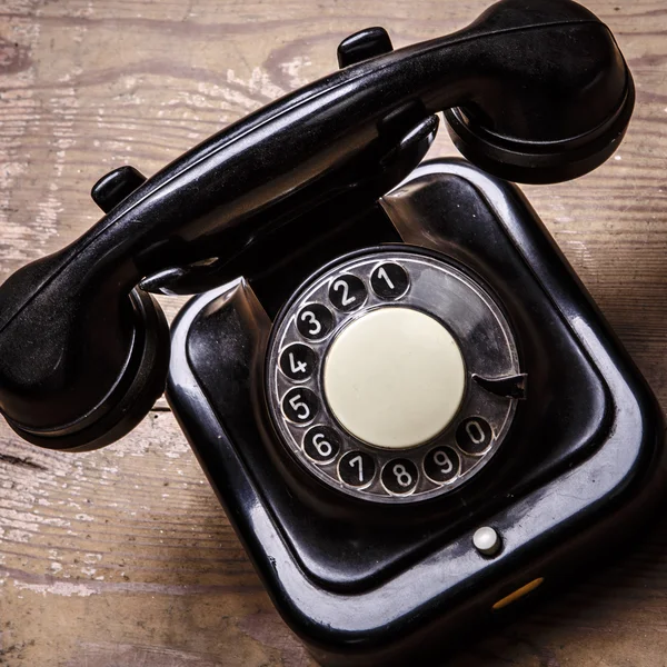 Teléfono negro viejo con polvo y arañazos en el suelo de madera —  Fotos de Stock