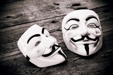 White and yellow anonymous masks on wood background