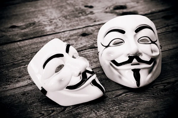 White and yellow anonymous masks on wood background