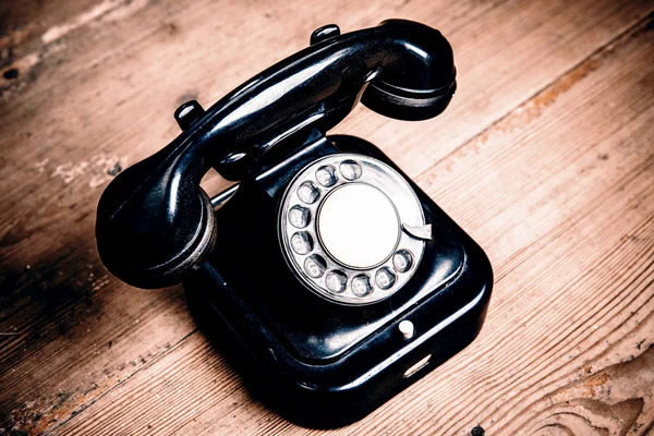 Telefone preto velho com poeira e arranhões no chão de madeira — Fotografia de Stock