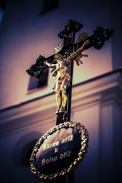 Croix noire avec Jésus d'or et chapelle comme arrière-plan — Photo