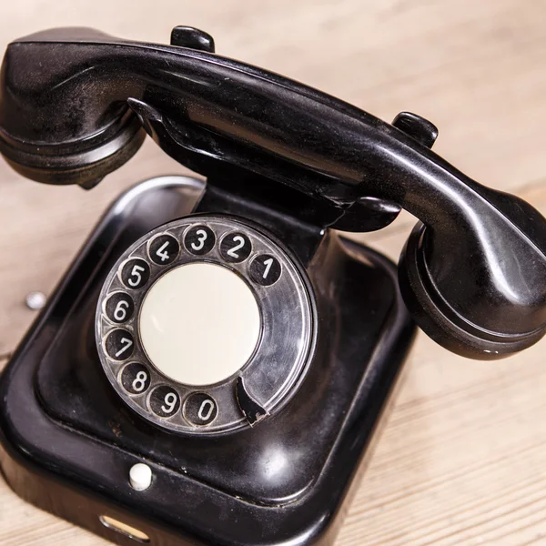 Old black phone with dust and scratches on wooden floor — Stock Photo, Image