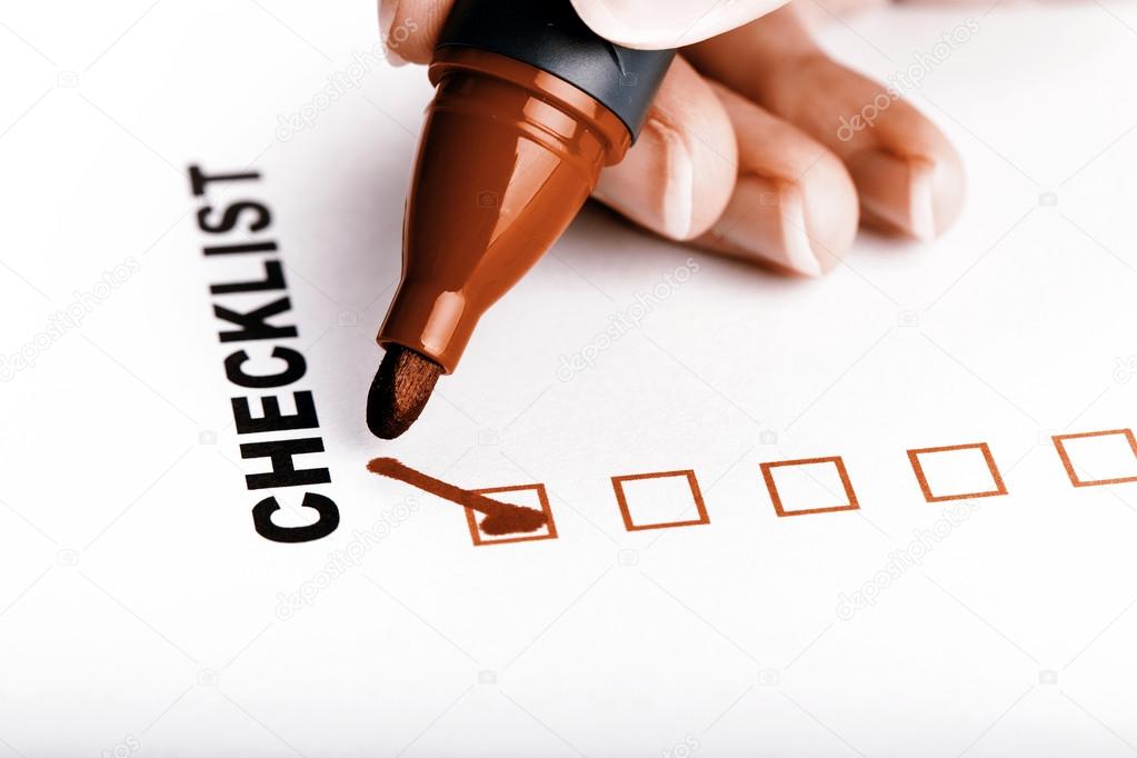 Checklist on white with marker and woman hand