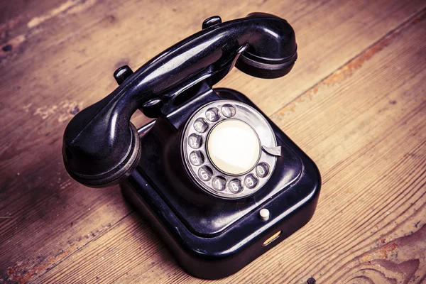 Telefone preto velho com poeira e arranhões no chão de madeira — Fotografia de Stock