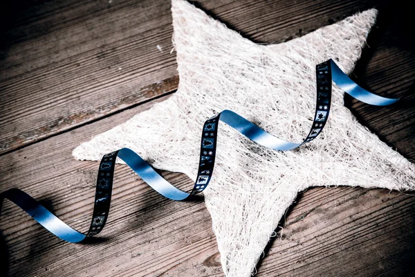 Hermosa decoración de Navidad - estrella blanca y cinta azul en el suelo de madera — Foto de Stock