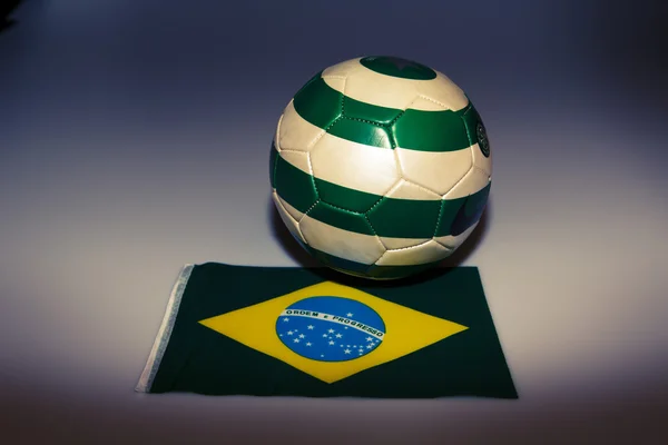 Bola de futebol verde e branco na bandeira do brasil — Fotografia de Stock