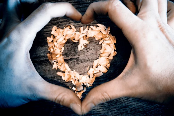 Un corazón de pétalos acostado en una mesa de madera y manos —  Fotos de Stock