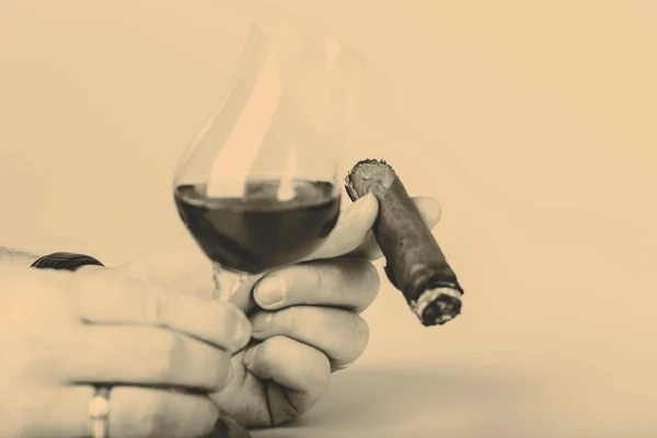 Gamla brandy i glas och cigarr i manlig hand på vit bakgrund — Stockfoto