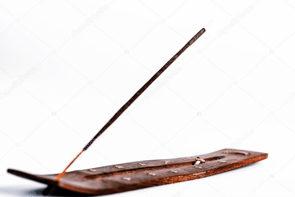 Incense stick on a wooden support on a white background