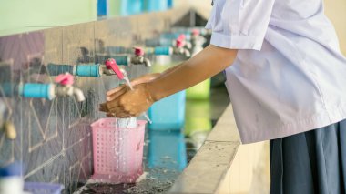 Okula gitmeden önce Corona virüsünün (Covid-19) yayılmasını önlemek için el yıkama alanı. Sağlık hizmeti konsepti. Yeni normal eğitim. Musluğa seçici odaklanma