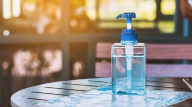 Corona virüsünün yayılmasını önlemek için el temizliği için mavi alkol jeli şişesi (Covid-19), müşterilerin giriş servisini kafeye yerleştirin. Sağlık sigortası konsepti. Yeni normal yaşam tarzı.