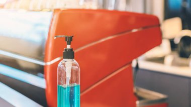 Corona virüsünün yayılmasını önlemek için el temizliği için mavi alkol jeli şişesi (Covid-19), müşterilerin giriş servisini kafeye yerleştirin. Sağlık sigortası konsepti. Yeni normal yaşam tarzı.