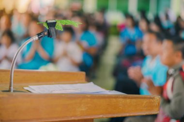Okul konferans salonundaki podyumdaki masaüstü mikrofon standına yerleştirilmiş yapay yaprak.