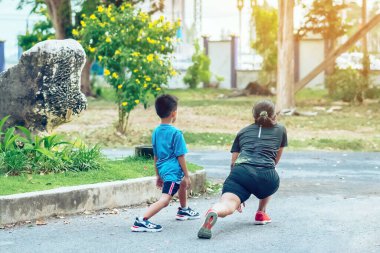 Sportif ve mutlu bir annenin oğlunu bahçede egzersiz yapmadan önce esneme hareketleri yaparken izlemesi. Atletik aile dışarıda birlikte egzersiz yapıyor. Çocuk bakımı spor aktivitesi konsepti