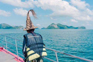 Tekne güvertesinde dinlenen ve güneşli bir günde güzel tropikal adaya bakan turistler..