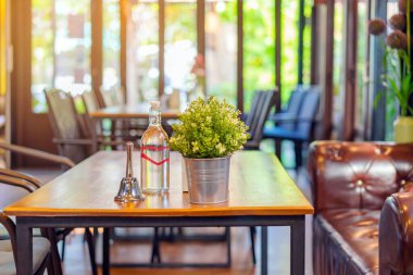 Garsonu aramak için küçük bir zil ve alüminyum bir tencerede suni çiçekler ve kahve dükkanındaki bir masaya yerleştirilmiş su şişesi..